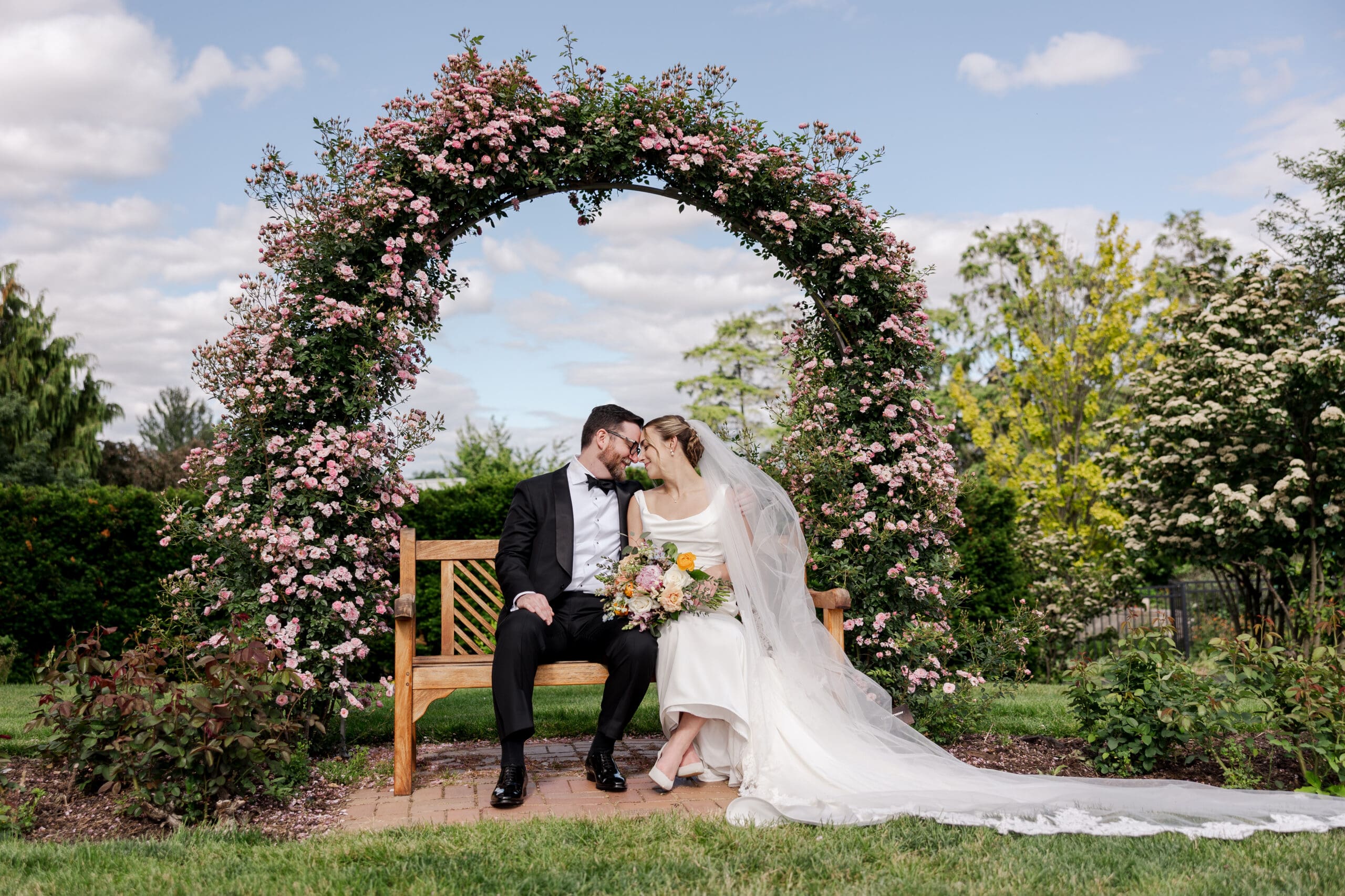 image of a bride and groom sitting on a bench in a flower garden