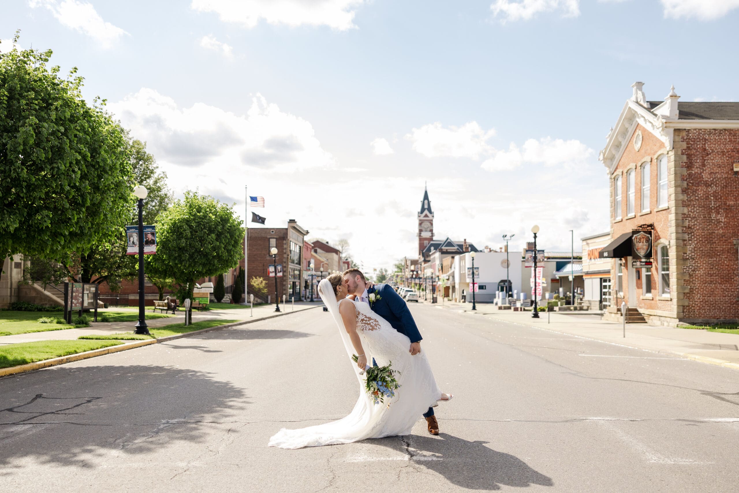 groom dipping a bride back for a kiss in the middle of the street