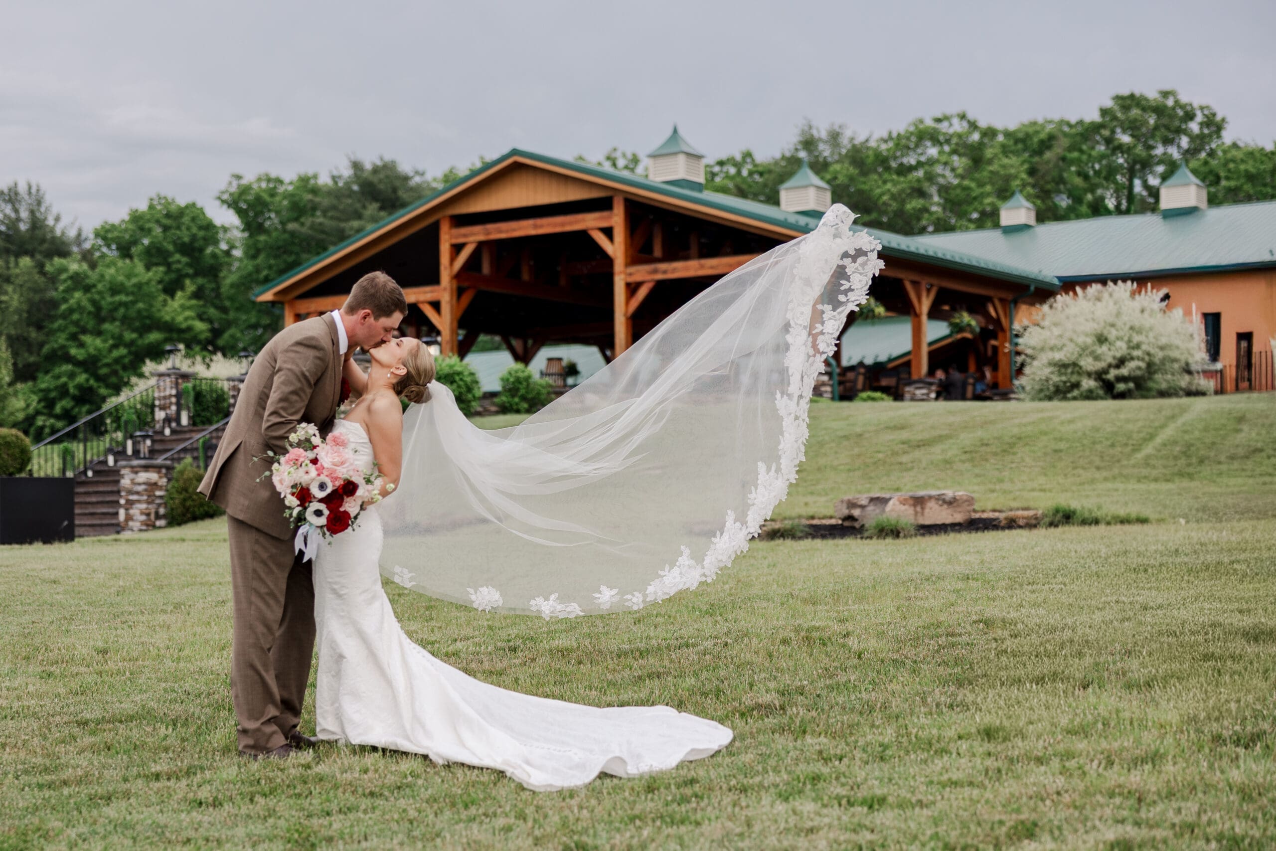 photo of bride and groom kissing with a long veil flowing behind them