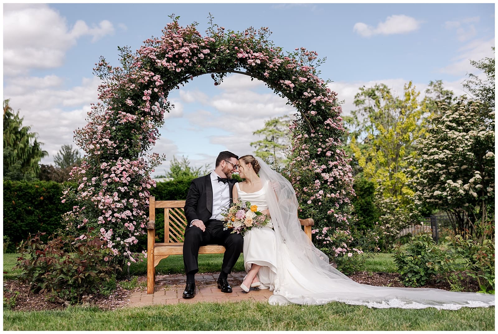 inamge of a bride and groom sharing a romantic moment under a flower arch